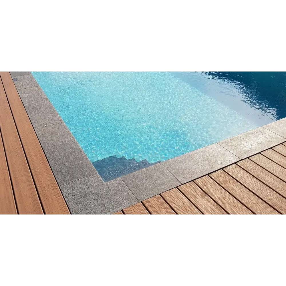 Klar blå poolvatten med grå stenplattor och trädäck i Natura Kiruna paket